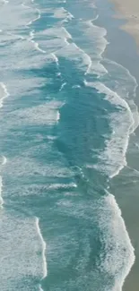 Aerial view of turquoise ocean waves gently hitting a sandy beach.