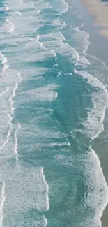 Aerial view of serene turquoise ocean waves crashing gently on a sandy beach.