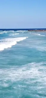 Peaceful ocean waves with turquoise water and clear blue sky.