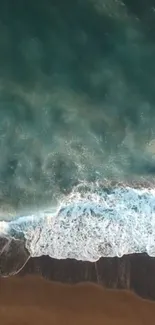 Aerial view of ocean waves along a serene beach with teal water and sandy shore.