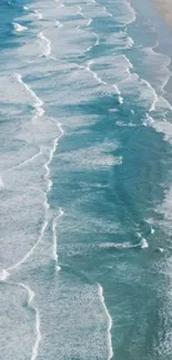 Aerial view of ocean waves meeting sandy beach.