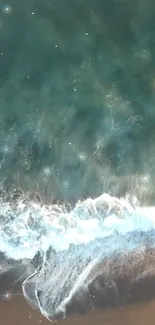 Aerial view of ocean waves gently touching sandy shore with teal waters.