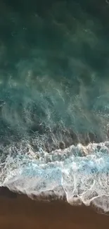 Aerial view of ocean waves meeting the sandy beach, in tranquil turquoise hues.