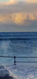 Serene ocean waves under a sunset sky with a railing in the foreground.