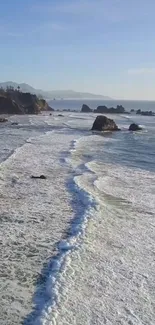 Aerial view of ocean waves crashing on a rocky shoreline at sunset.