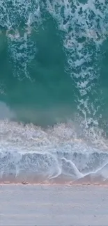 Aerial view of turquoise ocean waves gently lapping against a sandy beach.