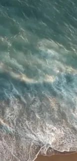 Aerial view of teal ocean waves crashing on a sandy beach, full of serene beauty.