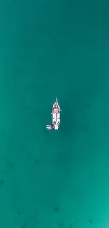 Aerial view of a yacht in the serene teal ocean, radiating tranquility.