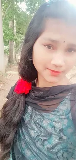 Serene outdoor portrait of a young woman with a floral hair accessory.