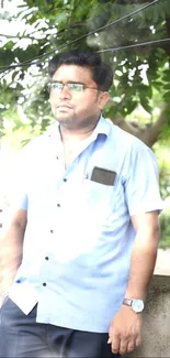 Man in a calming outdoor setting with lush green foliage.