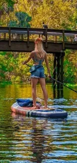 Paddleboarder on a tranquil river surrounded by green foliage.