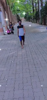 Man walking in a tree-lined park pathway with sparkles.