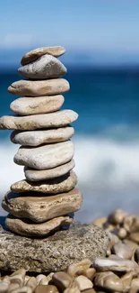 A balanced stack of pebbles by the sea with a blue ocean background.