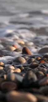 Close-up of beach pebbles with waves and foam in the background.