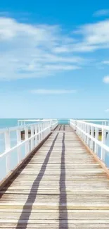 Peaceful pier extending into the ocean under a blue sky.