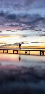 Serene pier at sunset with vibrant sky and reflections.