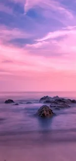 Serene pink sunset over a calm ocean with rocks and a pastel sky.