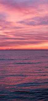 Pink sunset over a serene ocean creates a tranquil mobile wallpaper.