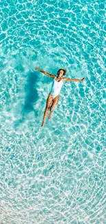 Person floats in a serene, clear pool under bright sunlight.