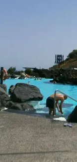 Serene poolside scene with blue waters and natural rocks under a clear sky.