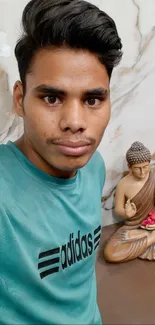 Young man with Buddha statue on marble background.