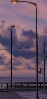 Purple dusk sky with street lamps and clouds by the ocean.