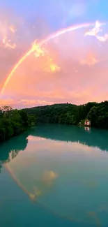 Vibrant rainbow over tranquil lake with lush greenery and sunrise sky.