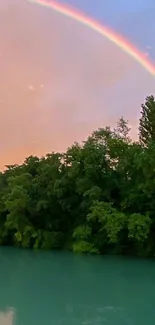 Mobile wallpaper of a rainbow over a lush forest and turquoise lake at sunset.