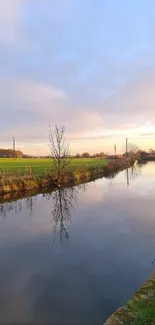 Serene river at sunset with tree reflections in calm water.