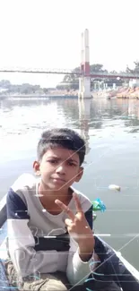 Boy on a boat with peace sign, river and bridge background.