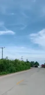 Open road under blue sky with green trees and serene ambiance.