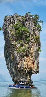 Majestic rock with boat on calm blue sea