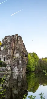 Rock formations reflecting in a tranquil lake under a clear blue sky.