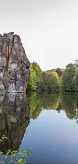 Rock formations reflected in calm water with surrounding greenery.