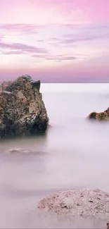 Serene sunset over rocky beach with calm ocean waters.