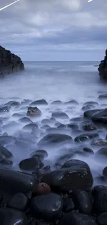 Rocky coastal view with misty waves and dark blue tones.