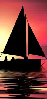 Silhouette of sailboat at vibrant sunset on ocean.