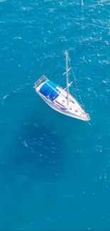 Aerial view of sailboat on tranquil blue ocean waters, perfect for mobile wallpaper.