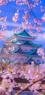 Stunning wallpaper of cherry blossoms framing a Japanese castle under a blue sky.