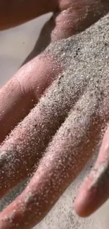 Close-up of a hand covered in sand, evoking a serene beach atmosphere.