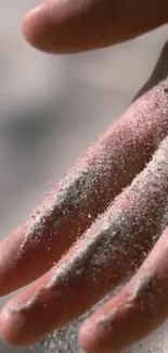 Close-up of a hand covered in sand, featuring soft beige tones and natural light.