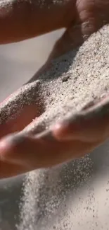 Hand gently letting sand fall through fingers.