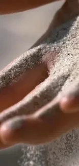 Sand gently falling through open hand wallpaper.