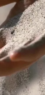 Hands letting fine sand flow gently through fingers.