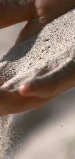 Hand gently holding and flowing sand in serene, natural light.