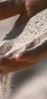 Hand pouring sand gently through fingers.