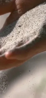 Close-up of hands letting fine sand flow gently, creating a serene and peaceful scene.