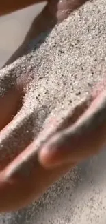 A close-up of a hand letting fine sand fall gracefully through the fingers.