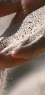 Close-up of a hand letting fine sand flow gently, creating a calming visual.