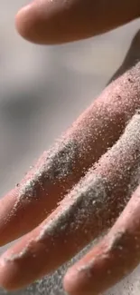 Close-up of sand-covered hand creating a serene texture.